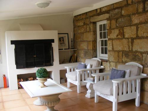 a living room with white chairs and a stone wall at Cleopatra Mountain Farmhouse in Fort Nottingham