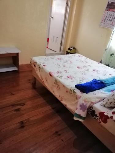 a small bedroom with a bed with a flowered sheet at Inn Maugay Bed and Bath in Sagada