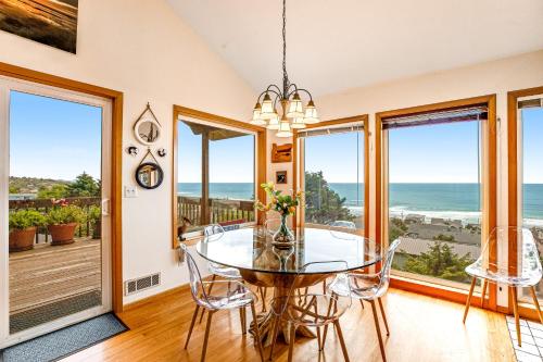 a dining room with a table and chairs and windows at Soaring High in Lincoln City