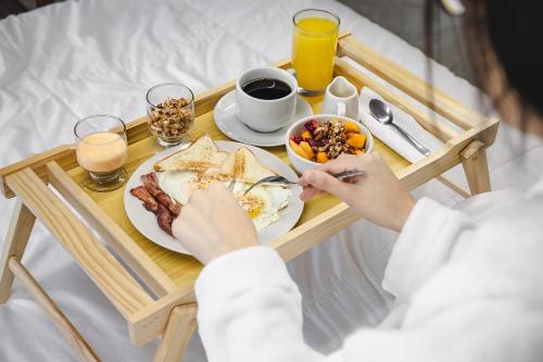 a breakfast tray with a plate of food on a bed at Hotel Santa Rosa in Chiclayo