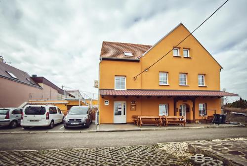 a yellow house with cars parked in a parking lot at Chaloupka víno sklep U Palečků in Zaječí