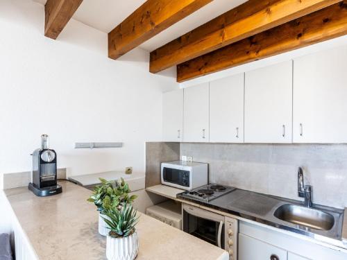 une cuisine avec des armoires blanches, un évier et un micro-ondes dans l'établissement Studio Les Adichats by Interhome, à Saint-Palais-sur-Mer