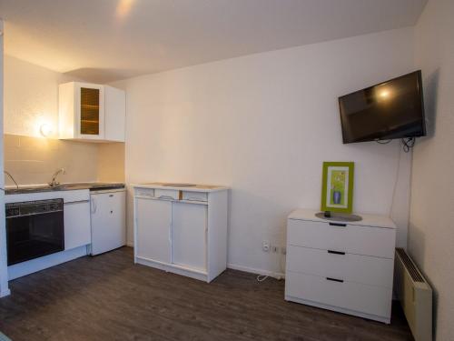 Il comprend une cuisine avec des placards blancs et une télévision murale. dans l'établissement Studio Côte d'Azur-10 by Interhome, à Bormes-les-Mimosas
