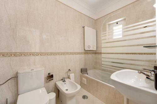 a bathroom with a white toilet and a sink at Palmeiras Reais 110 in Portimão
