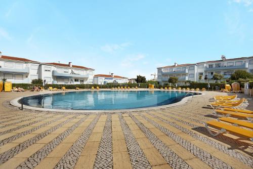 a large swimming pool with lounge chairs and buildings at Palmeiras Reais 110 in Portimão