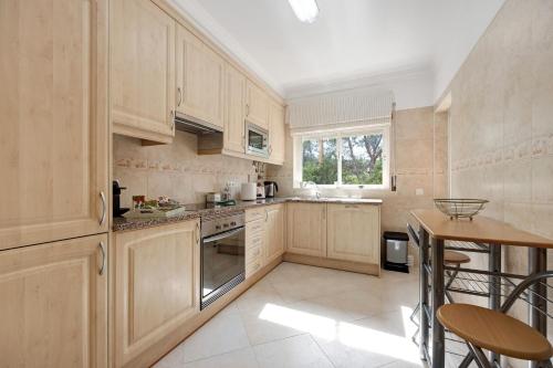 a kitchen with wooden cabinets and a table and chairs at Palmeiras Reais 110 in Portimão