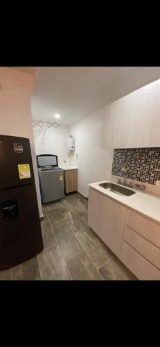 uma cozinha com um frigorífico preto e um lavatório em Apartamento confortable,lujoso y cómodo em Sabaneta