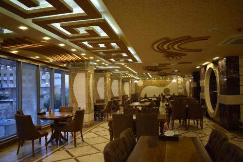 Royal Eagle Hotel في النجف: مطعم فيه طاولات وكراسي في الغرفة