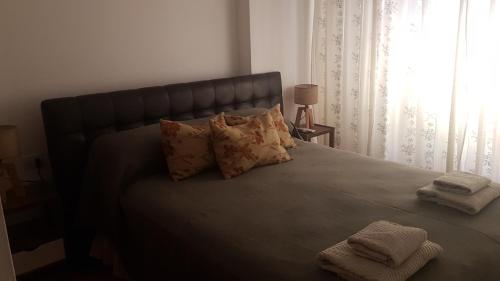 um quarto com uma cama grande com almofadas e uma janela em Mi depto en Córdoba II . em Córdoba