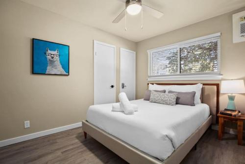 a bedroom with a white bed with a cat picture on the wall at 7-Minute Walk to Deep Eddy Pool, Parking, and Grill in Austin