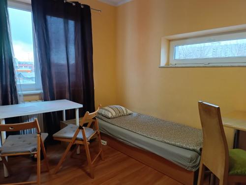 mały pokój z łóżkiem, stołem i krzesłami w obiekcie Hostel Sunrise Liwska w Warszawie