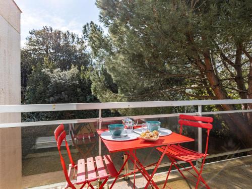 d'une table rouge et de deux chaises sur un balcon. dans l'établissement Apartment Les Ecureuils by Interhome, à La Palud