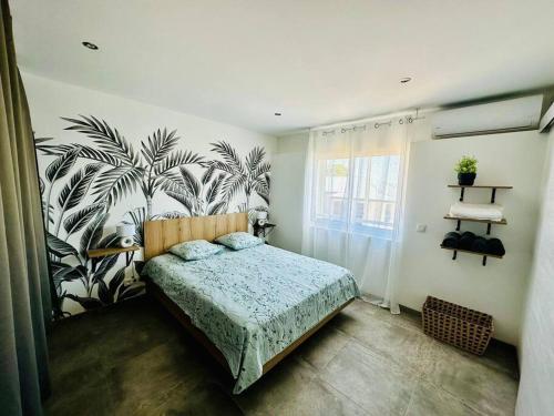 - une chambre avec un lit aux motifs tropicaux sur le mur dans l'établissement La Kaz Eden * * * *, à Les Cocos