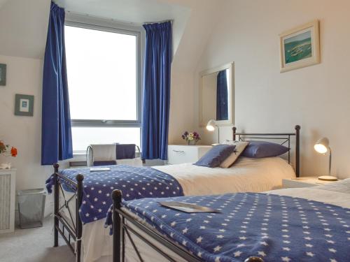 a bedroom with two beds and a large window at Spindrift in Coverack