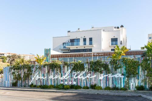 uma cerca com graffiti em frente a um edifício em You and the sea na Ericeira