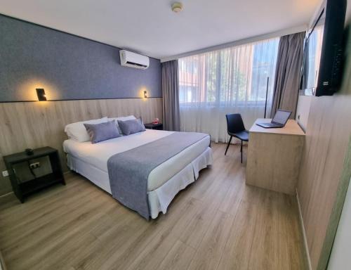 Habitación de hotel con cama grande y escritorio. en Panamericana Hotel Providencia, en Santiago