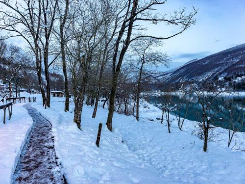 a snow covered path next to a river with trees at Apartment Albergo Diffuso - Cjasa Ustin-5 by Interhome in Barcis
