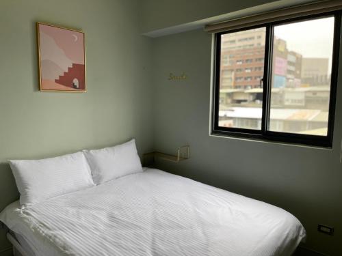 een kleine slaapkamer met een bed en een raam bij 極旅inn in Taichung