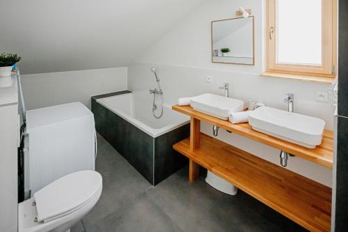 a bathroom with two sinks and a tub and a toilet at Chata pod Stupkou in Mýto pod Ďumbierom