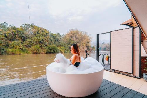 a woman sitting in a bath tub on a deck at VeeVaree Riverkwai Resort in Ban Kaeng Raboet