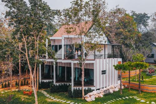 a large white house with a balcony and trees at VeeVaree Riverkwai Resort in Ban Kaeng Raboet