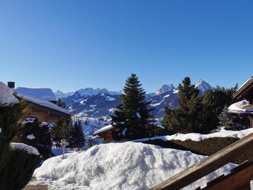 ein Schneehaufen auf einem Zaun mit Bergen im Hintergrund in der Unterkunft Apartment Les Hivernants - EG links by Interhome in Gstaad
