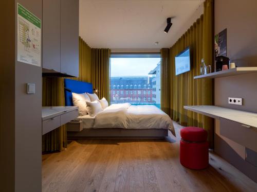 a bedroom with a bed and a large window at b'mine hotel Düsseldorf in Düsseldorf