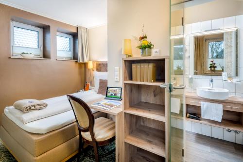 una camera con letto, lavandino e specchio di Hotel Stadtidyll & Dependancen a Rotenburg an der Wümme