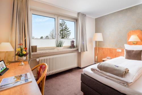 a hotel room with a bed and a desk and a window at Hotel Stadtidyll & Dependancen in Rotenburg an der Wümme