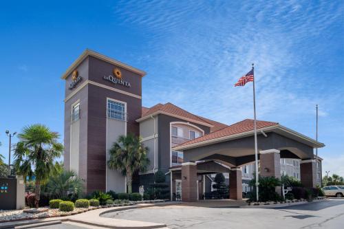 a hotel with a flag in front of a building at La Quinta by Wyndham Prattville in Prattville