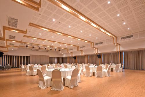 北芭堤雅的住宿－Prima Hotel Pattaya，一个带白色桌椅的大型宴会厅