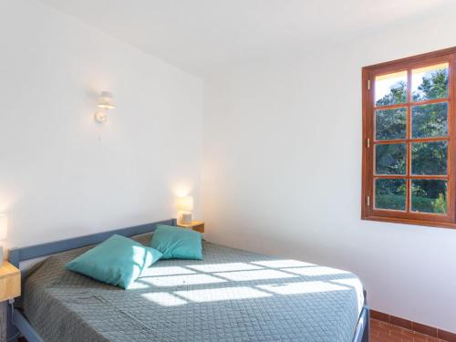 une chambre avec un lit avec des oreillers bleus et une fenêtre dans l'établissement Apartment Saint Clair by Interhome, au Lavandou