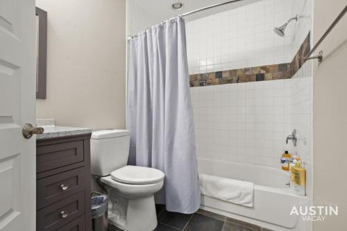 a bathroom with a white shower curtain and a toilet at Gorgeous Home in Heart of Zilker with Full Kitchen in Austin