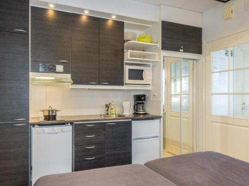 eine Küche mit schwarzen Schränken und weißen Geräten in der Unterkunft Holiday Home Levi star i- ap-1110 by Interhome in Sirkka