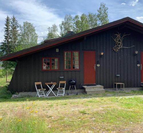 a black house with chairs and a grill in front of it at Hytte nær Ål 