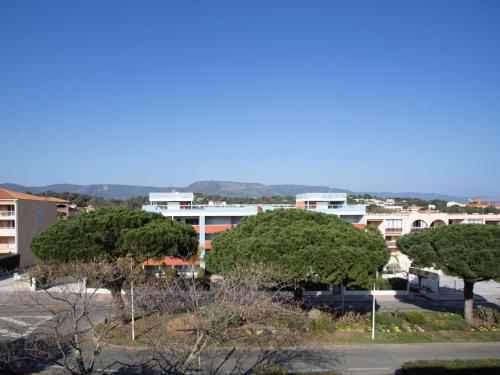 un groupe d'arbres dans un parking avec des bâtiments dans l'établissement Apartment Côte d'Azur-13 by Interhome, à Bormes-les-Mimosas