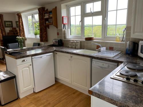 a kitchen with white cabinets and a sink and windows at Rural Retreat in Idyllic Countryside - fishing & walks in Hawkhurst