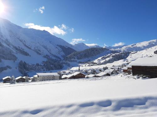 a village covered in snow with mountains in the background at Apartment Alpetta by Interhome in Tschamut