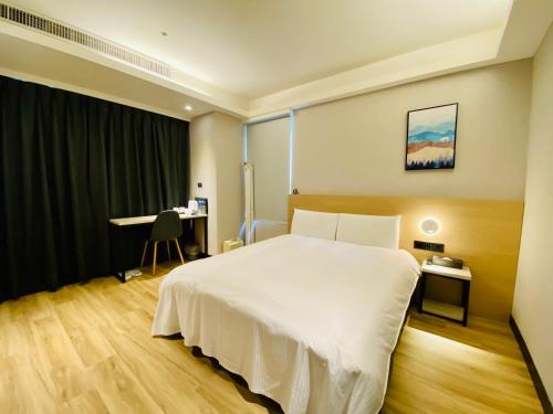 a bedroom with a large white bed and a desk at Hub Hotel Songshan Inn in Taipei