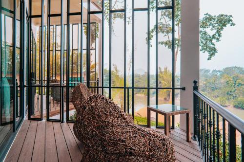a room with a chair on a balcony with a view at VeeVaree Riverkwai Resort in Ban Kaeng Raboet