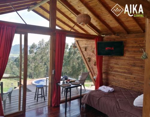 1 dormitorio con 1 cama y balcón con mesa en AIKA Reserva Glamping Tabio, en Tabio