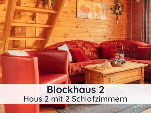 - un salon avec deux canapés rouges et une table dans l'établissement Der Fuchsbau - 3 separate Blockhäuser - ruhige Lage - 50m bis zum Wald - eingezäunter Garten, à Bad Sachsa