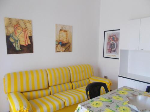 a living room with a yellow couch and a table at Appartamento Eucalpti Baia Verde By Nonsolomare Case Vacanze srlu in Baia Di Gallipoli