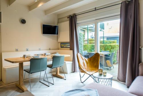 een woonkamer met een tafel en stoelen en een raam bij De Friese Antillen in Hollum