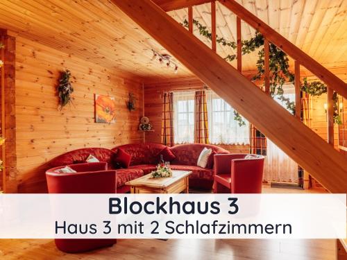 Elle comprend un salon doté d'un mobilier rouge et de murs en bois. dans l'établissement Der Fuchsbau - 3 separate Blockhäuser - ruhige Lage - 50m bis zum Wald - eingezäunter Garten, à Bad Sachsa