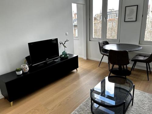 een woonkamer met een tv en een tafel en stoelen bij Apartment near central station in Antwerpen