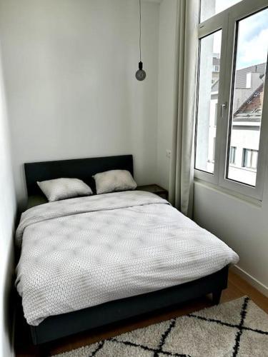 een bed in een witte kamer met een raam bij Apartment near central station in Antwerpen