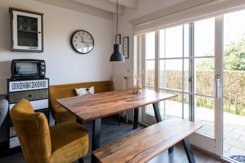 a dining room with a table and a clock on the wall at De Friese Antillen in Hollum