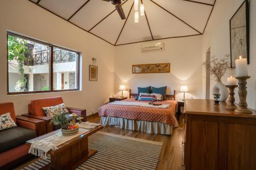 a bedroom with a bed and a couch and a table at LohonoStays Homestead, Corbett in Rāmnagar