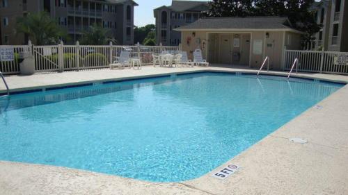 a large blue swimming pool with chairs and tables at Tilghman Shores D9 in Myrtle Beach